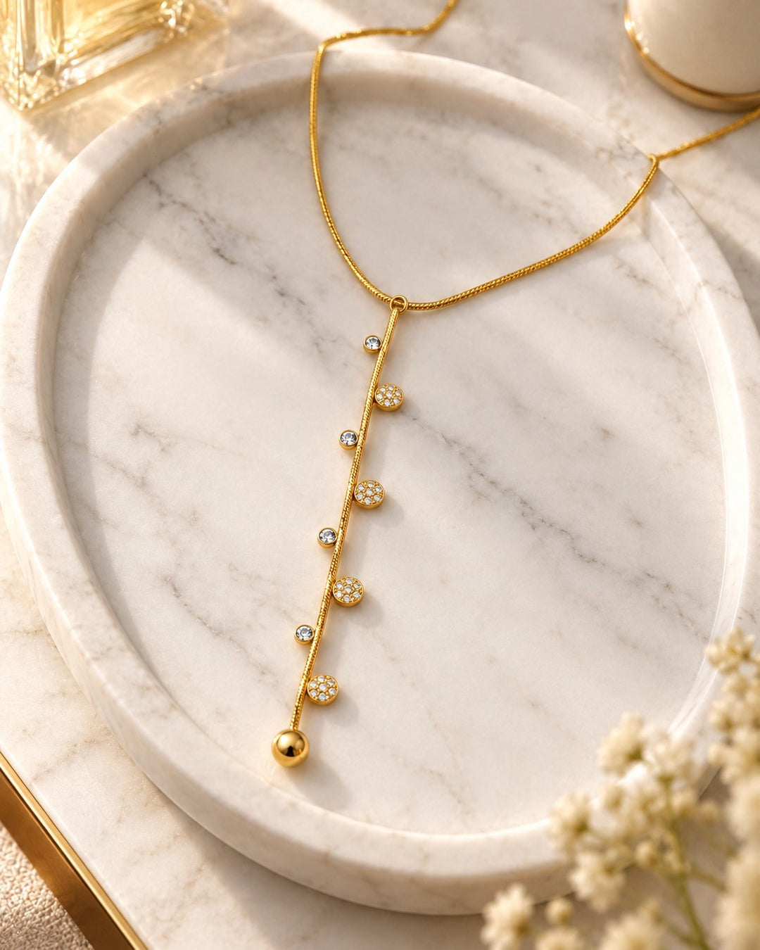 Elli Jewellery gold-plated dainty necklace featuring a vertical bar with sparkling crystal accents on a marble tray.