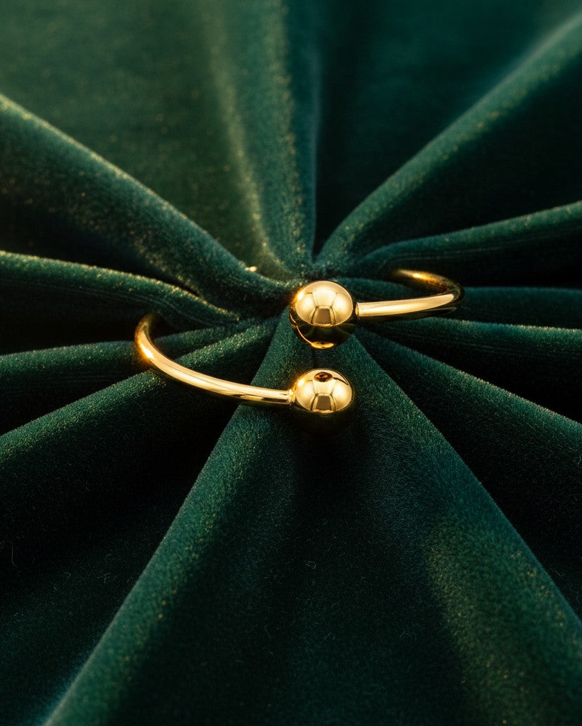 Elli Jewellery gold plated minimalist double ball ring on a dark green velvet background