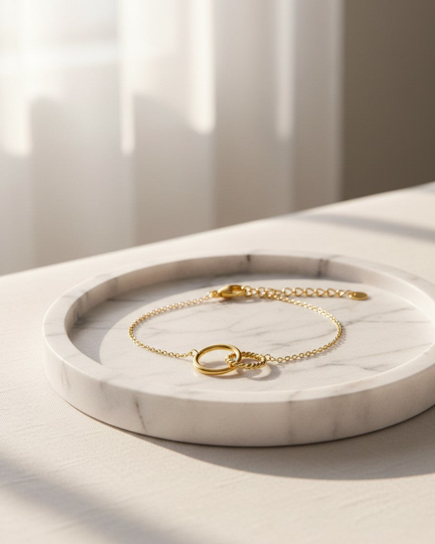 Elli Jewellery gold-toned anklet featuring two interlocking circles on a delicate chain, resting on a marble tray.