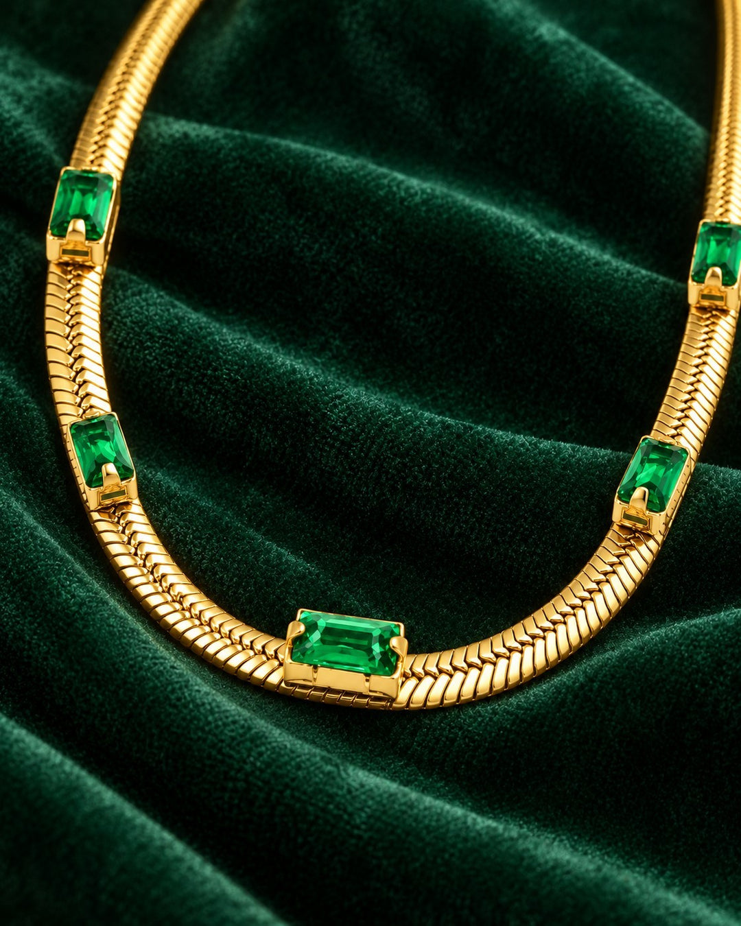 Elli Jewellery gold plated snake chain necklace with emerald green cubic zirconia stones on dark green velvet