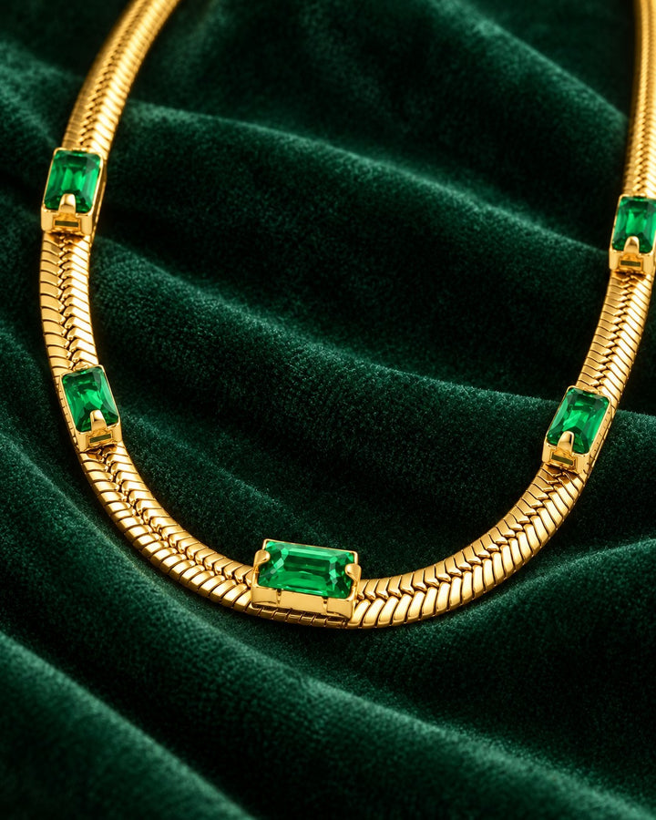 Elli Jewellery gold plated snake chain necklace with emerald green cubic zirconia stones on dark green velvet