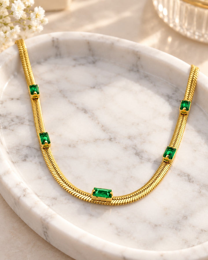 Elli Jewellery gold plated snake chain necklace featuring emerald green rectangular cubic zirconia stones on marble