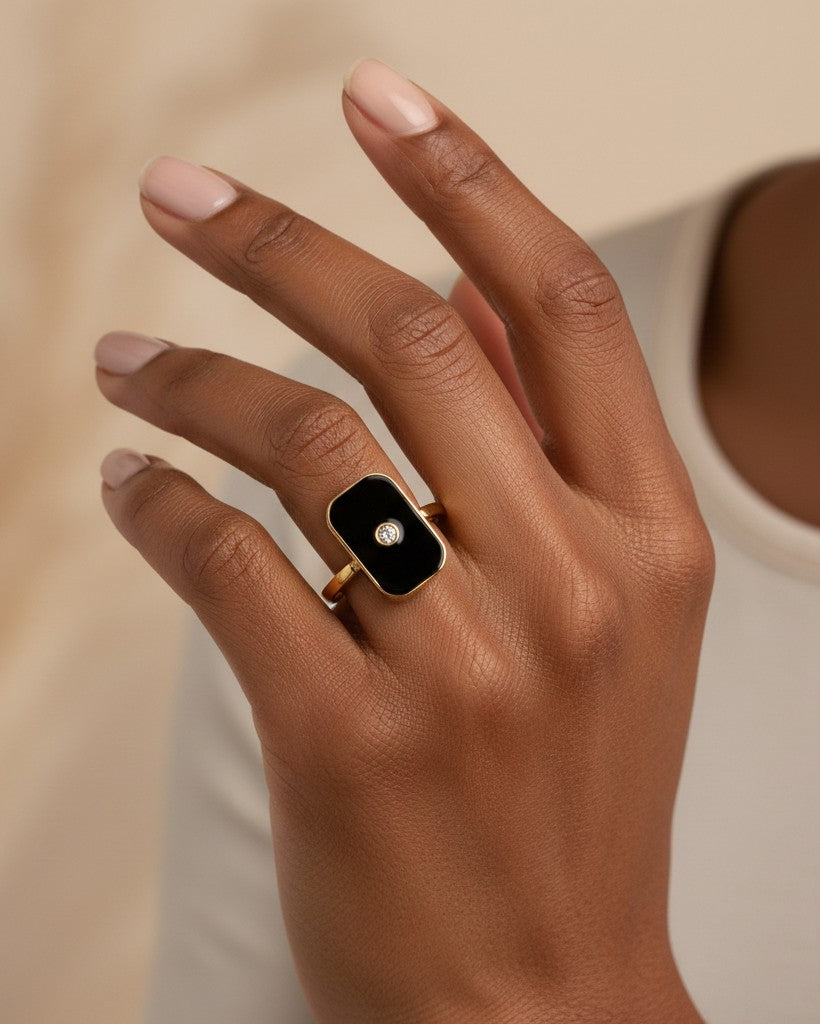 Elli Jewellery gold-plated rectangular statement ring with black enamel and a central stone on a model's finger