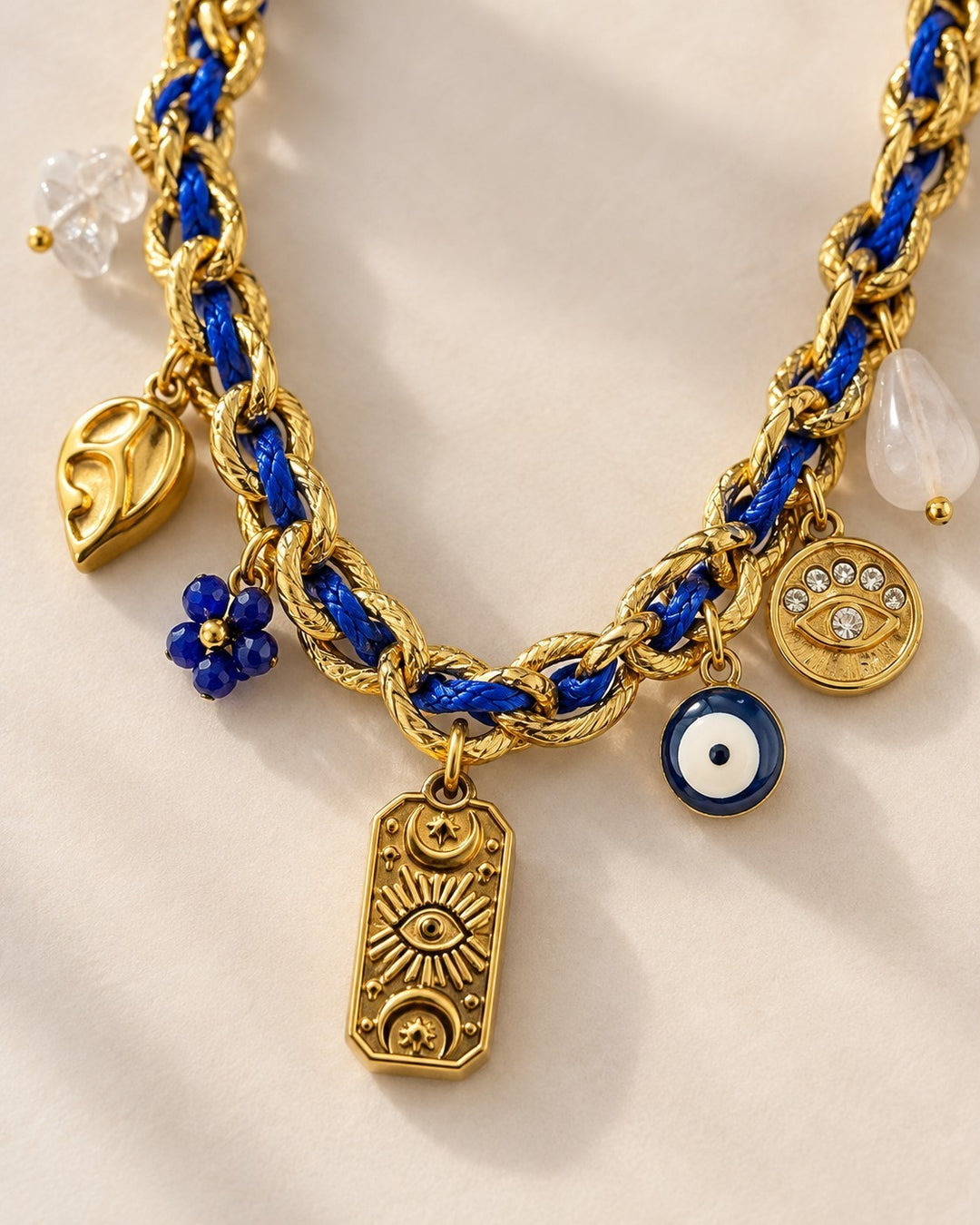 Elli Jewellery gold plated chain necklace with blue cord, evil eye charms, and celestial pendants on a neutral background