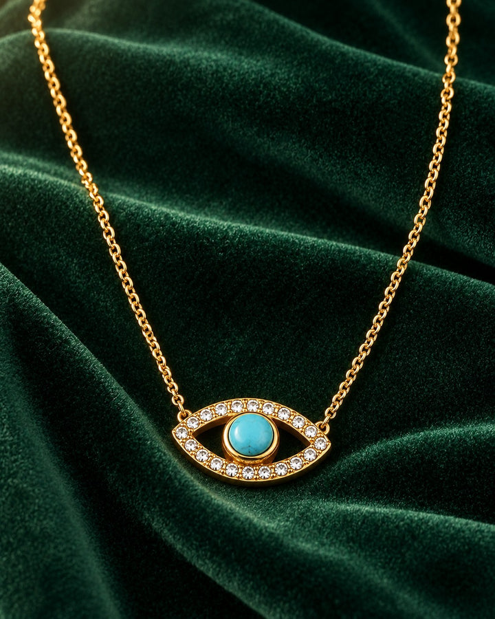 Elli Jewellery gold-plated evil eye necklace featuring a central turquoise stone and clear zirconia on green velvet