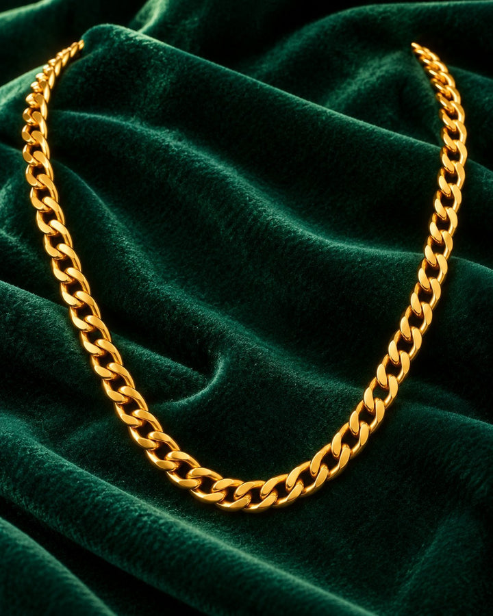 Elli Jewellery gold plated waterproof Figaro chain necklace resting on a luxurious dark green velvet fabric background.
