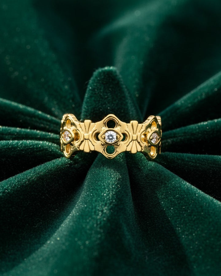 Elli Jewellery gold plated hollow floral statement ring with embedded crystals on a dark green velvet background