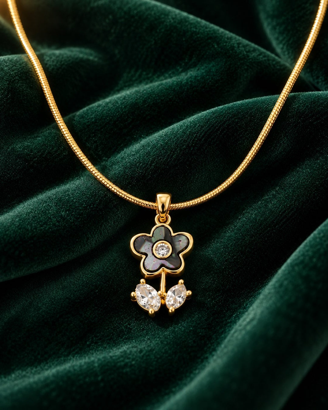 Elli Jewellery gold plated snake chain necklace with a floral pendant featuring cubic zirconia on green velvet