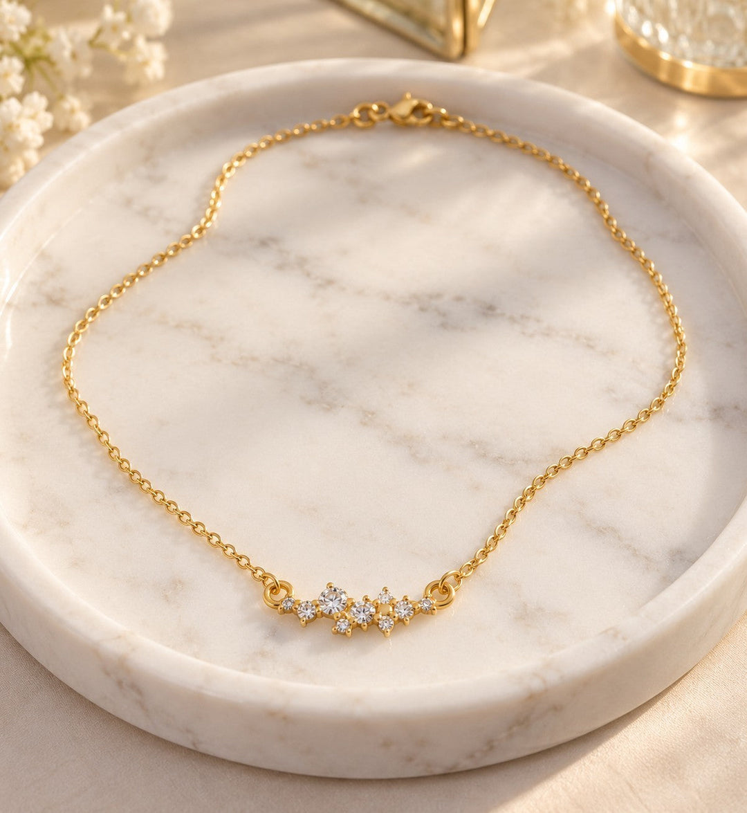 Elli Jewellery gold plated necklace with a delicate cubic zirconia flower pendant on a white marble tray