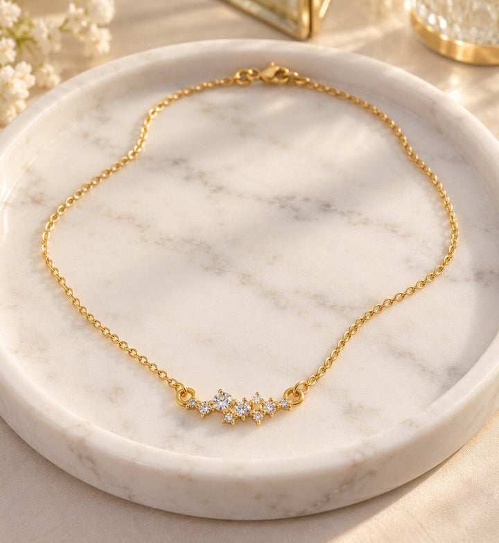 Elli Jewellery gold plated necklace with a delicate cubic zirconia flower pendant on a white marble tray