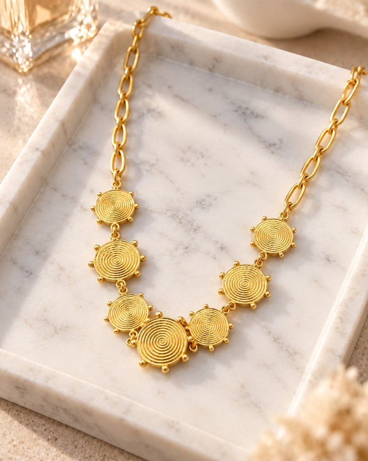 Elli Jewellery gold plated waterproof necklace featuring geometric spiral circle links on a marble tray.