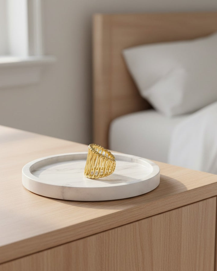 Elli Jewellery gold plated hollow geometric statement ring resting on a white marble tray in a bedroom setting.