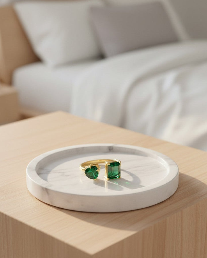 Elli Jewellery gold plated adjustable ring with green cubic zirconia crystals on a marble tray.