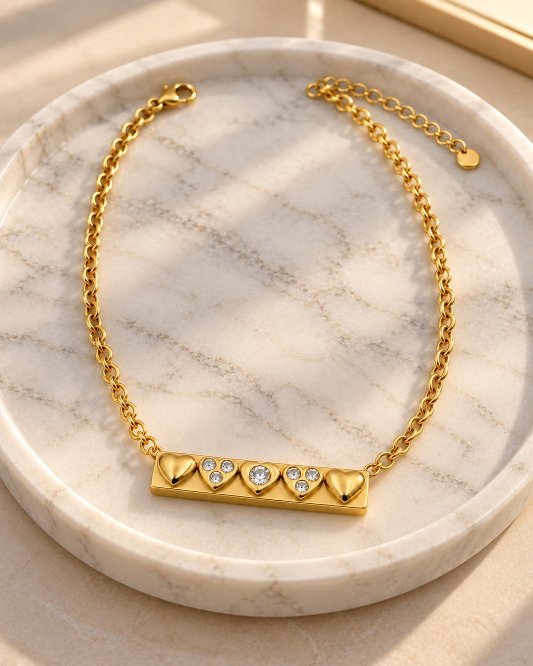 Elli Jewellery gold plated bar necklace featuring three heart charms and two sparkling crystals on a dainty chain.