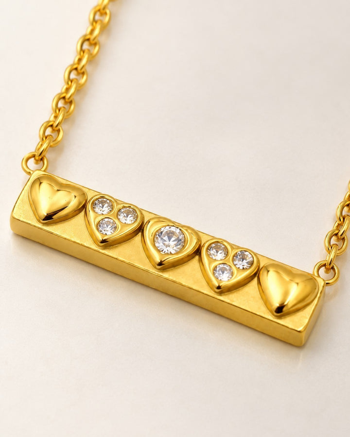Elli Jewellery gold plated bar necklace featuring three crystal-encrusted heart motifs and two smooth heart accents