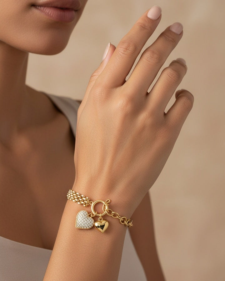 Elli Jewellery gold plated chain bracelet featuring a pavé heart charm and a smooth heart pendant on a model's wrist.