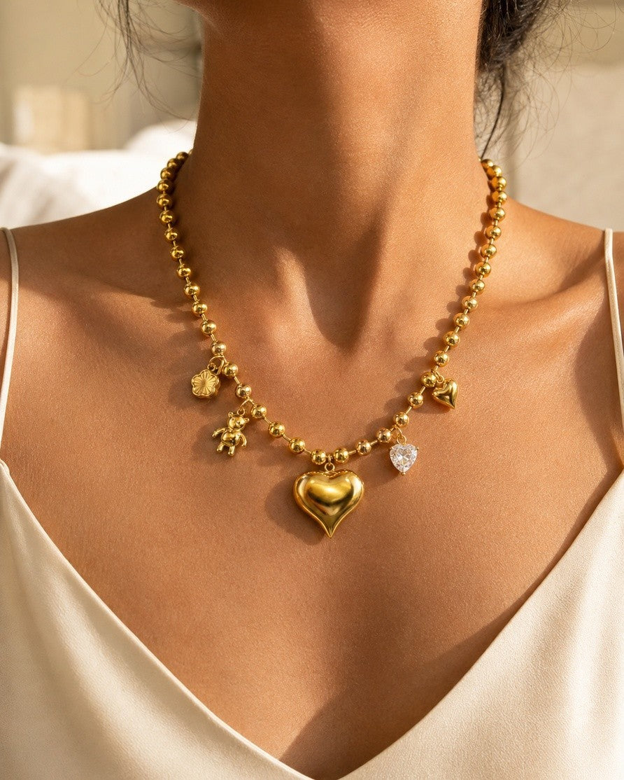 Elli Jewellery gold plated beaded chain necklace featuring a central heart charm, teddy bear, and crystal accents.