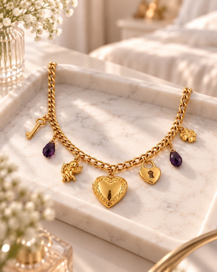 Elli Jewellery gold plated charm necklace featuring a heart locket, purple crystals, and cupid charm on marble tray.
