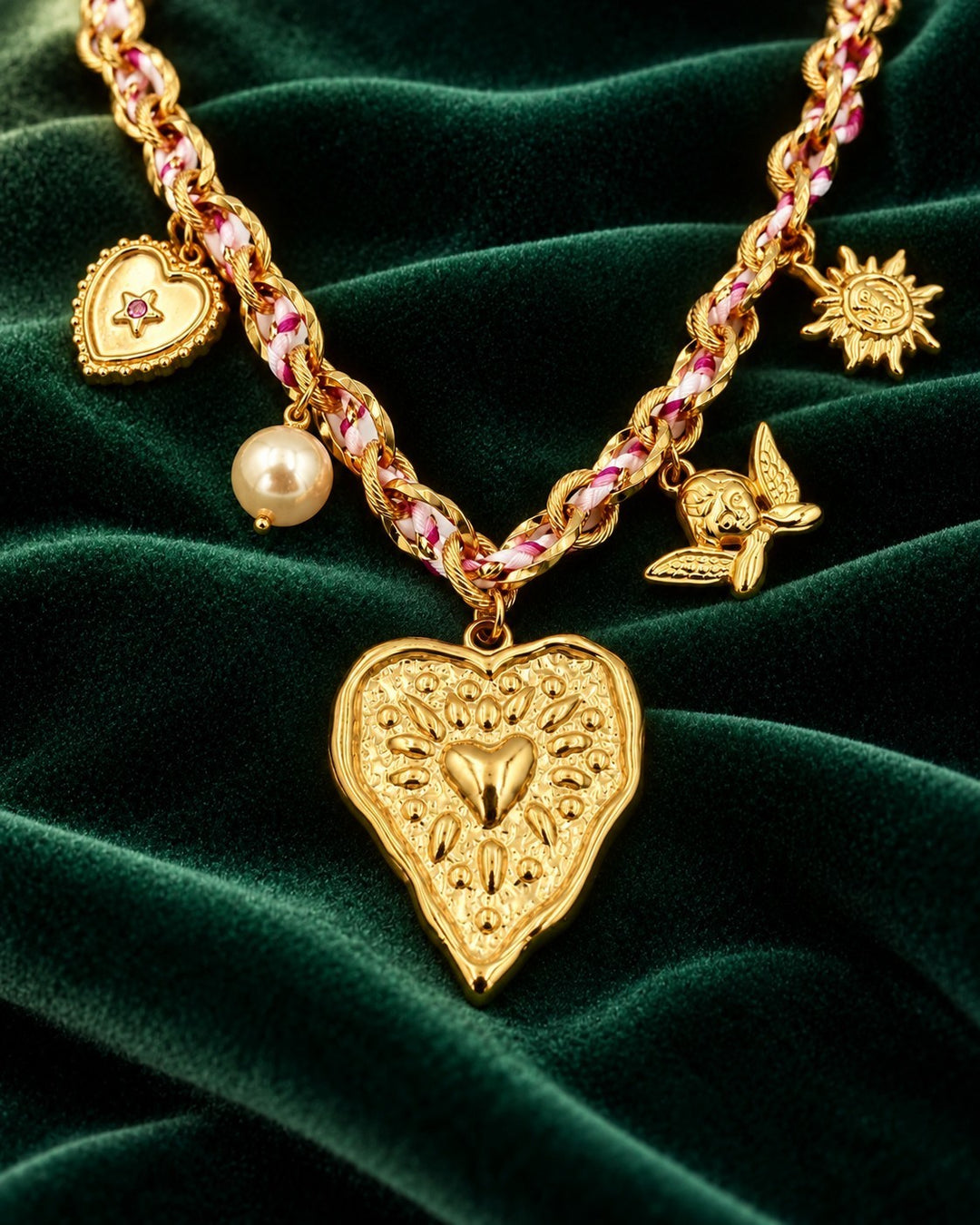 Elli Jewellery gold plated charm necklace featuring a heart beam pendant, pearl, angel, and sun charms on velvet