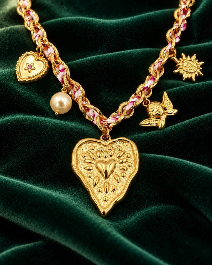 Elli Jewellery gold plated charm necklace featuring a heart beam pendant, pearl, angel, and sun charms on velvet