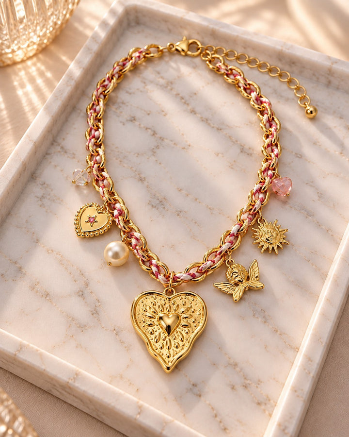 Elli Jewellery gold plated charm necklace featuring a large heart pendant, angel, sun, and pearl on a braided chain.