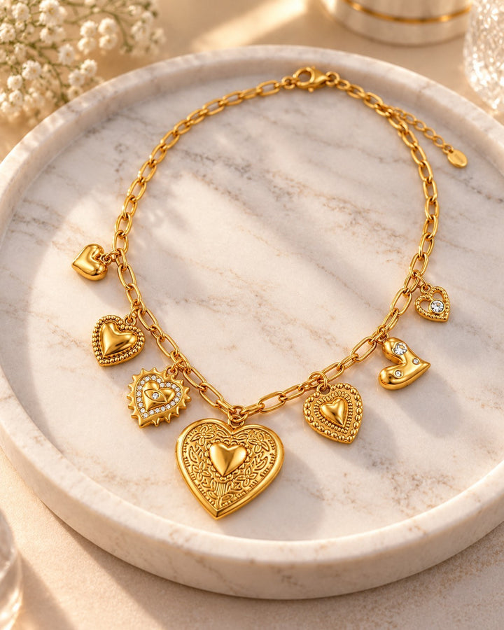 Elli Jewellery gold plated charm necklace featuring multiple heart pendants and crystals on a marble tray