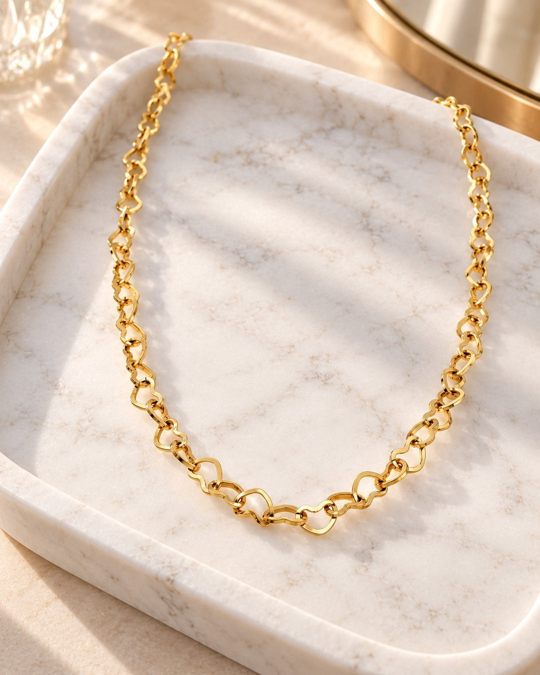 Elli Jewellery gold plated dainty heart link choker necklace resting on a white marble tray