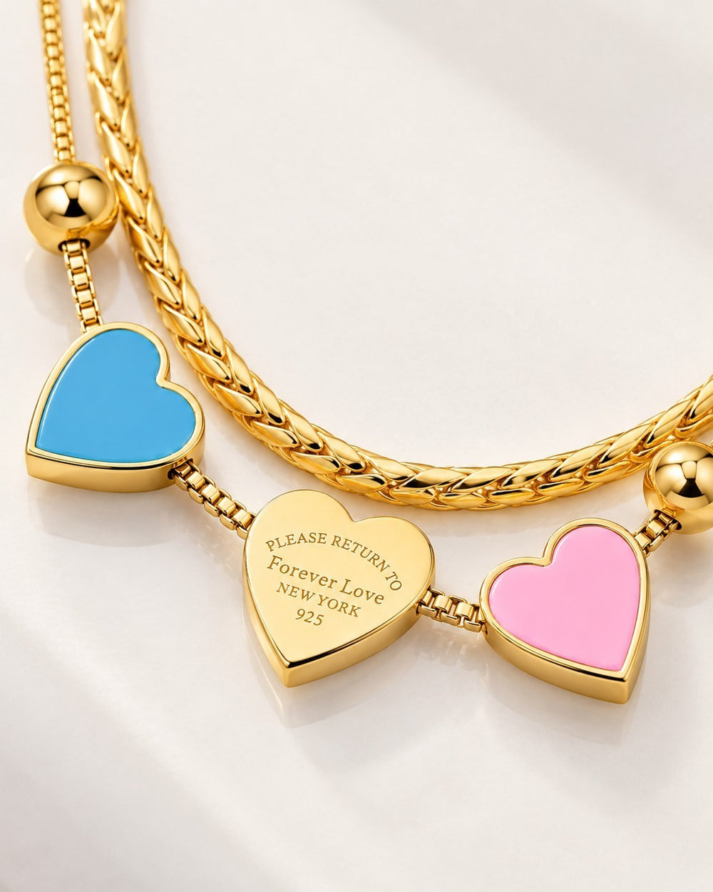 Elli Jewellery gold plated layered chain necklace featuring three heart charms in blue, engraved gold, and pink enamel.