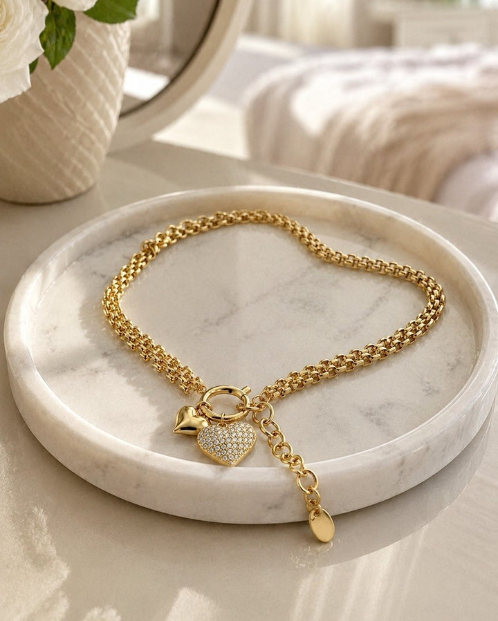 Elli Jewellery gold plated waterproof heart charm necklace with crystal accents on a marble tray