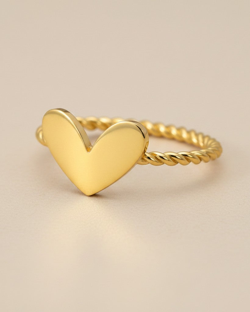 Elli Jewellery gold plated heart ring with a dainty twisted rope band on a neutral background