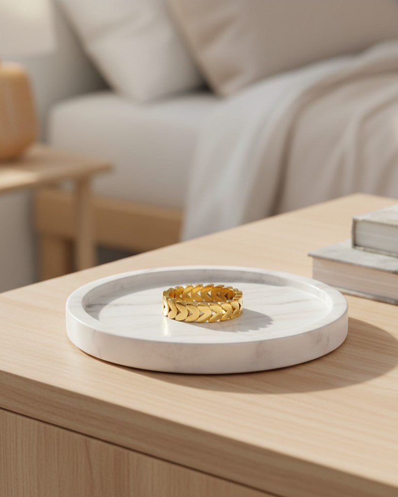 Elli Jewellery gold plated stacking ring featuring an intertwined heart pattern on a white marble tray.