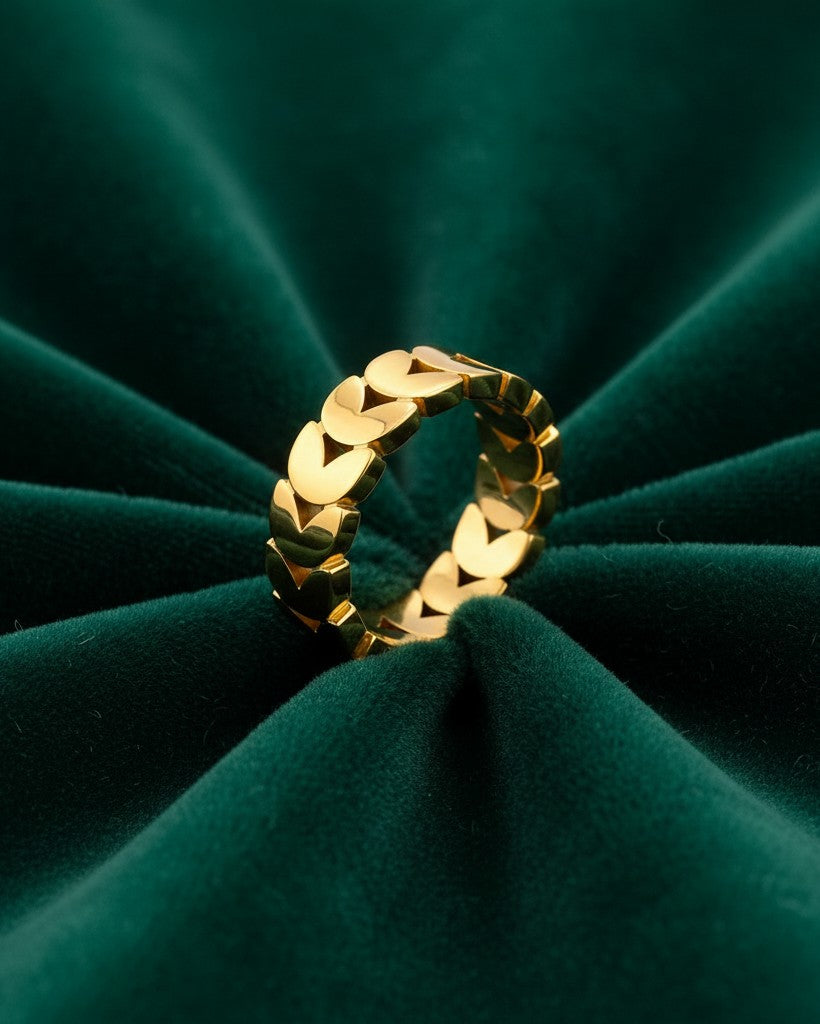 Elli Jewellery gold plated stacking ring featuring a delicate repeating heart pattern on a dark green velvet background