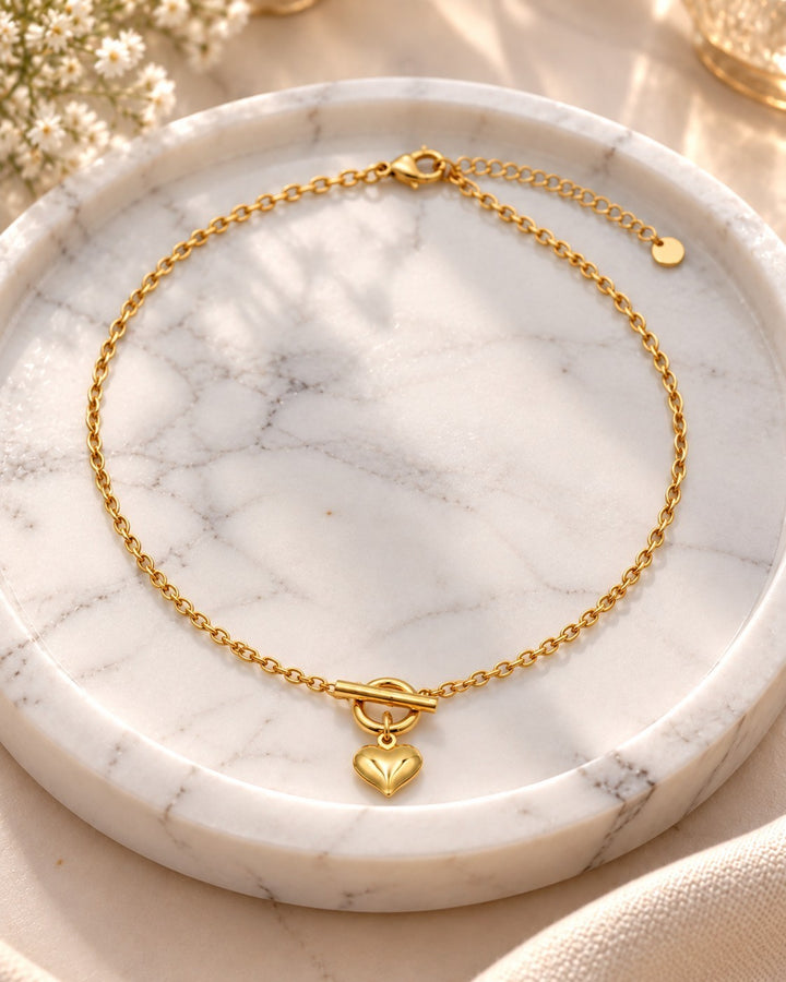 Elli Jewellery gold plated heart pendant necklace featuring a sleek chain and toggle clasp on a marble tray.