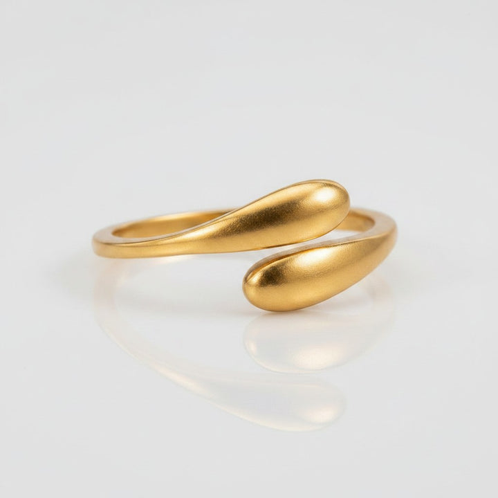 Elli Jewellery gold plated minimalist hug wrap ring with a sleek sculptural design on a reflective white surface.