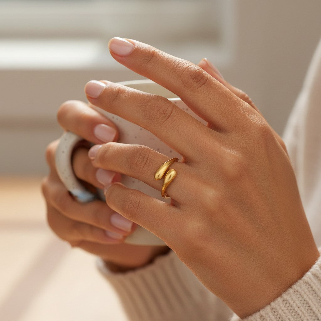 Elli Jewellery gold plated minimalist hug wrap ring worn on a finger while holding a ceramic mug.