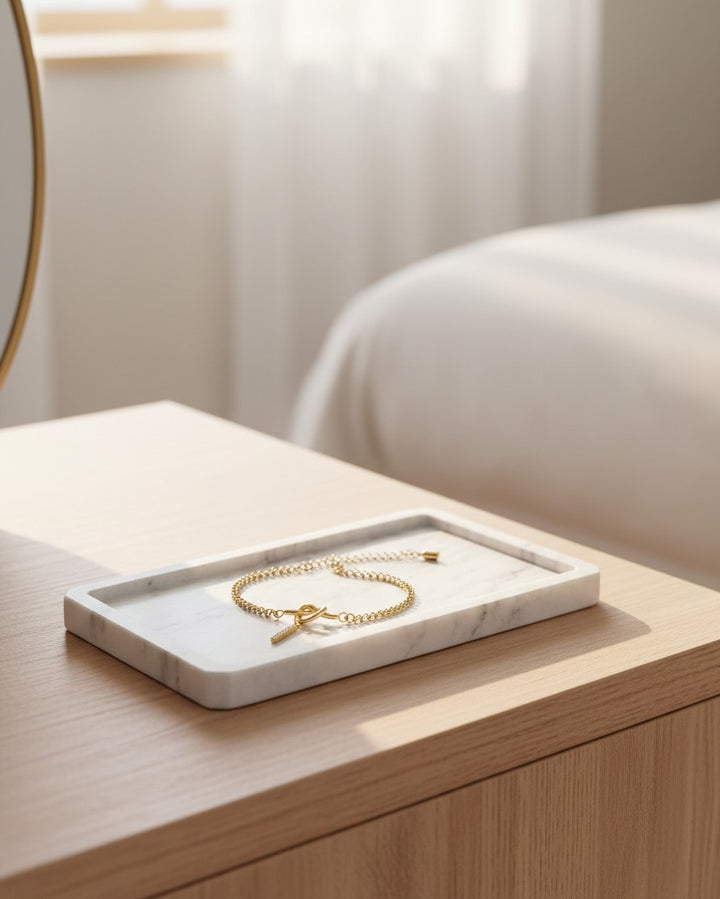 Elli Jewellery gold plated waterproof initial I charm bracelet with crystals resting on a white marble tray.