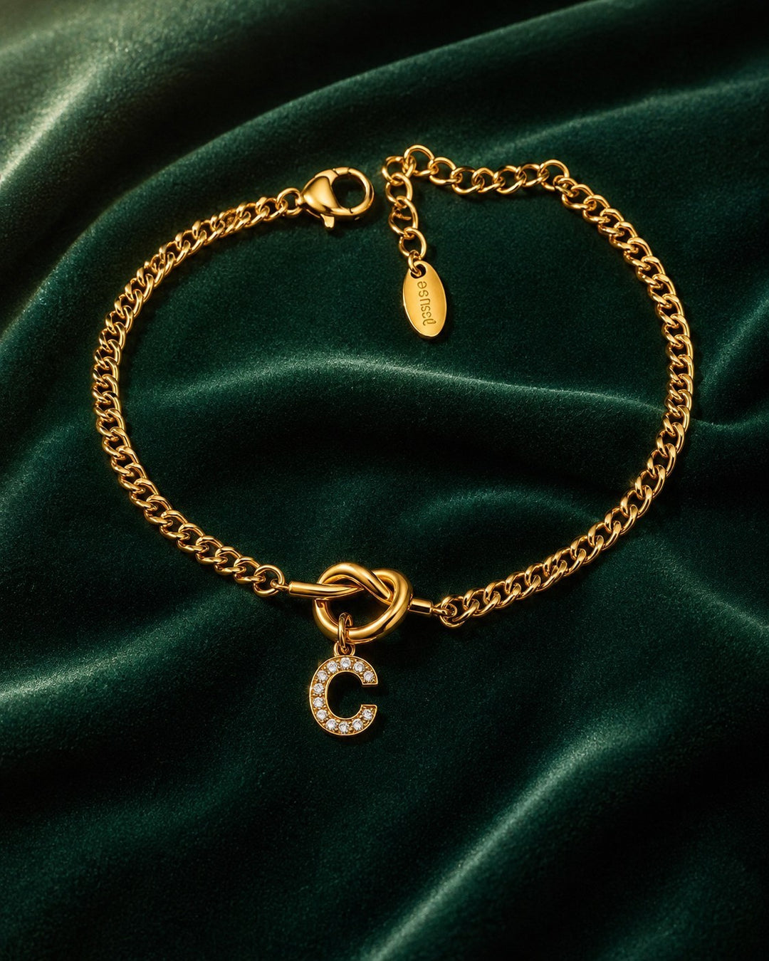 Elli Jewellery gold plated chain bracelet featuring a sparkling diamanté C initial charm on a dark green velvet background