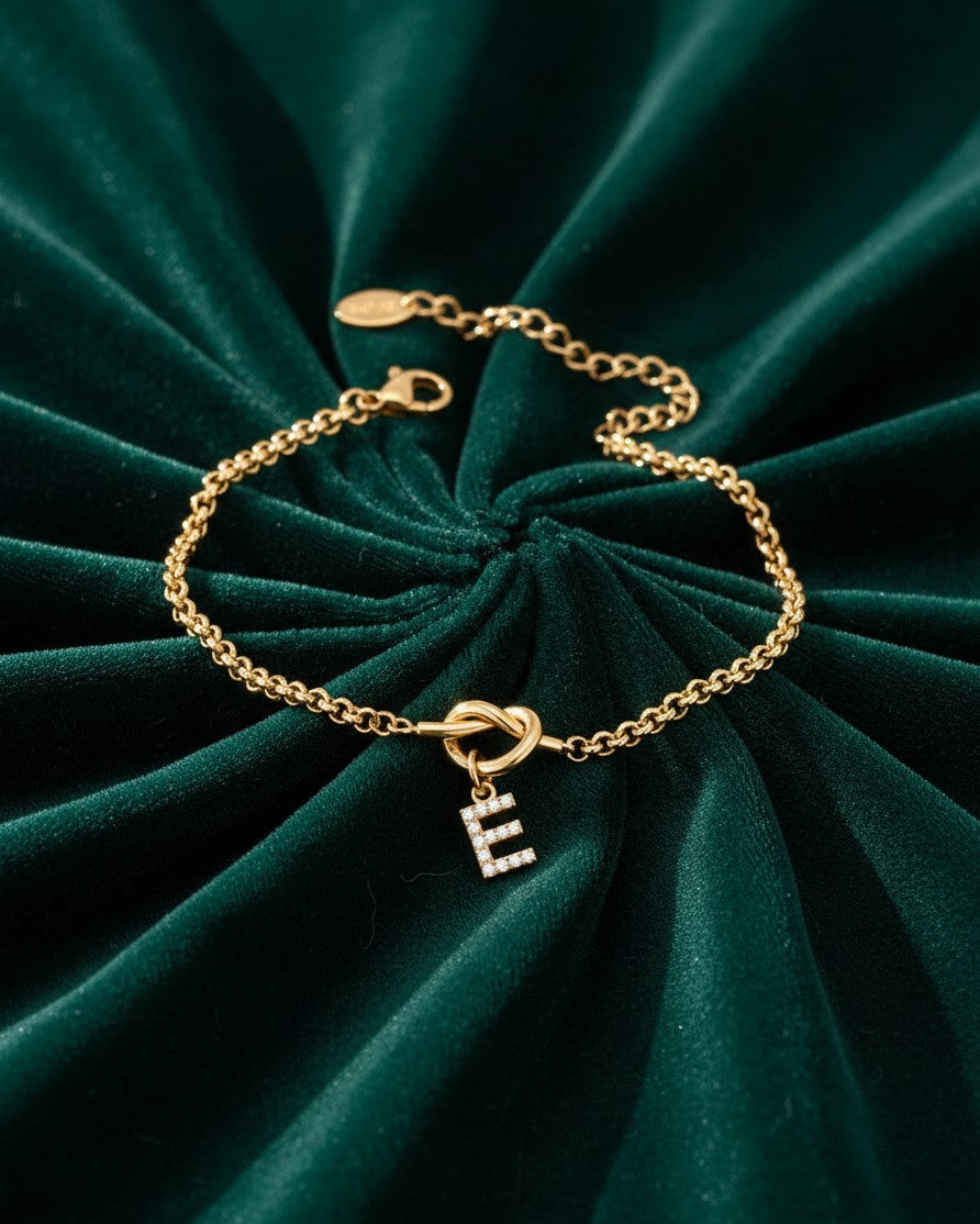 Elli Jewellery gold plated waterproof chain bracelet with a sparkling diamanté letter E charm on green velvet
