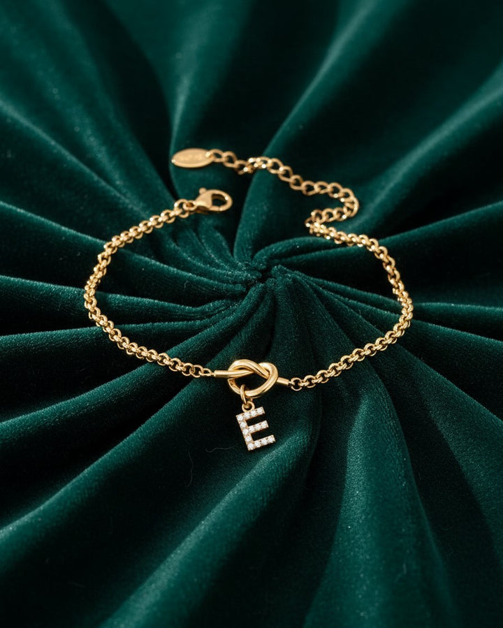 Elli Jewellery gold plated waterproof chain bracelet with a sparkling diamanté letter E charm on green velvet