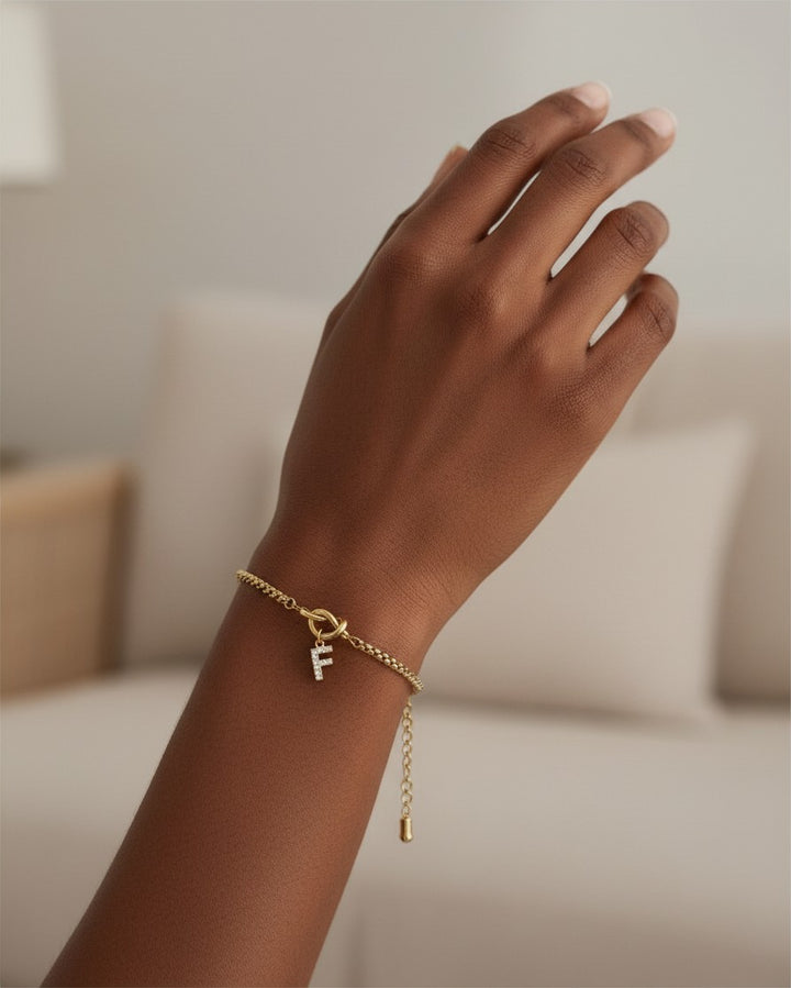 Elli Jewellery gold plated chain bracelet featuring a sparkling diamante initial F charm on a model's wrist.