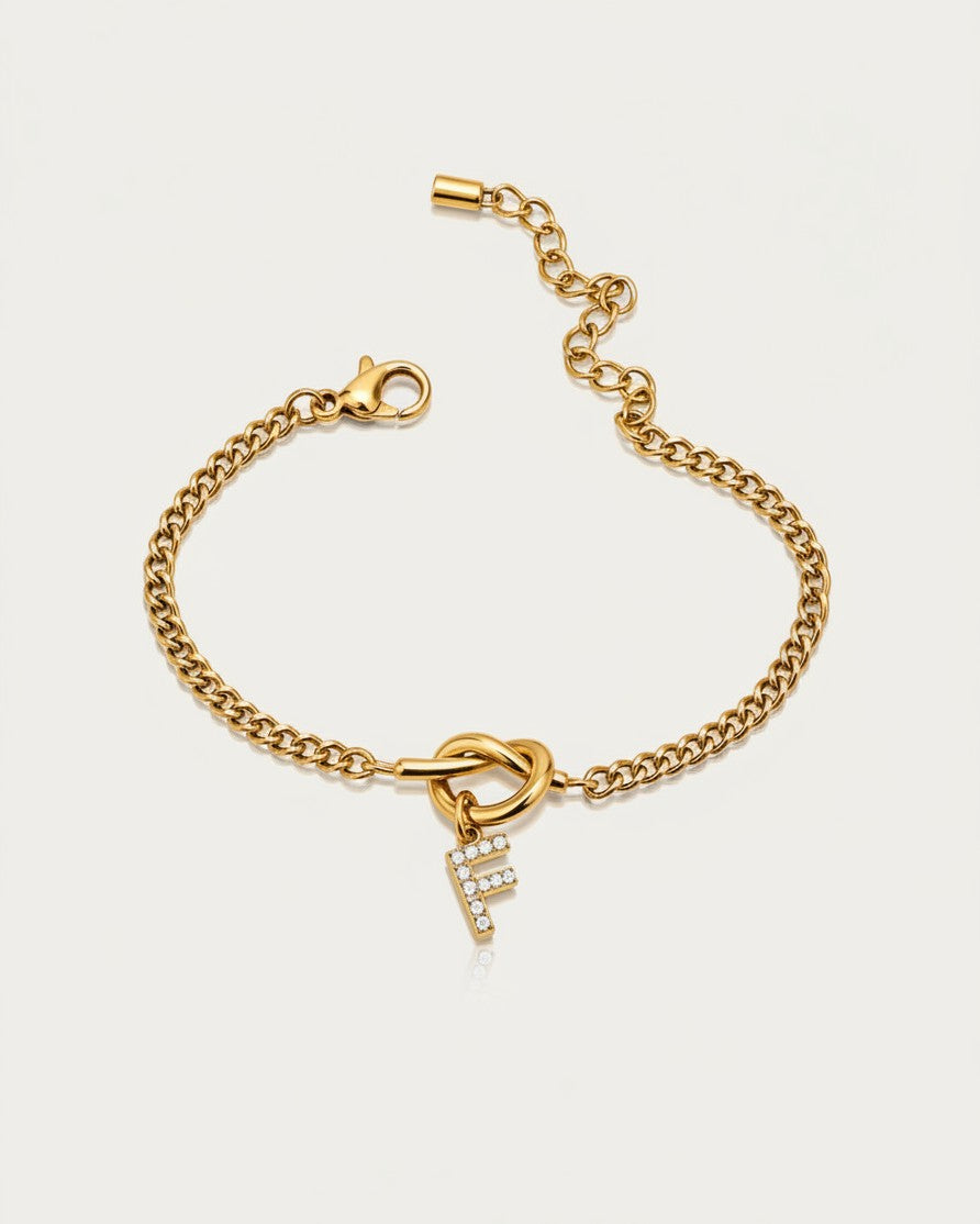 Elli Jewellery gold plated chain bracelet featuring a sparkling diamante initial F charm and a decorative knot detail.