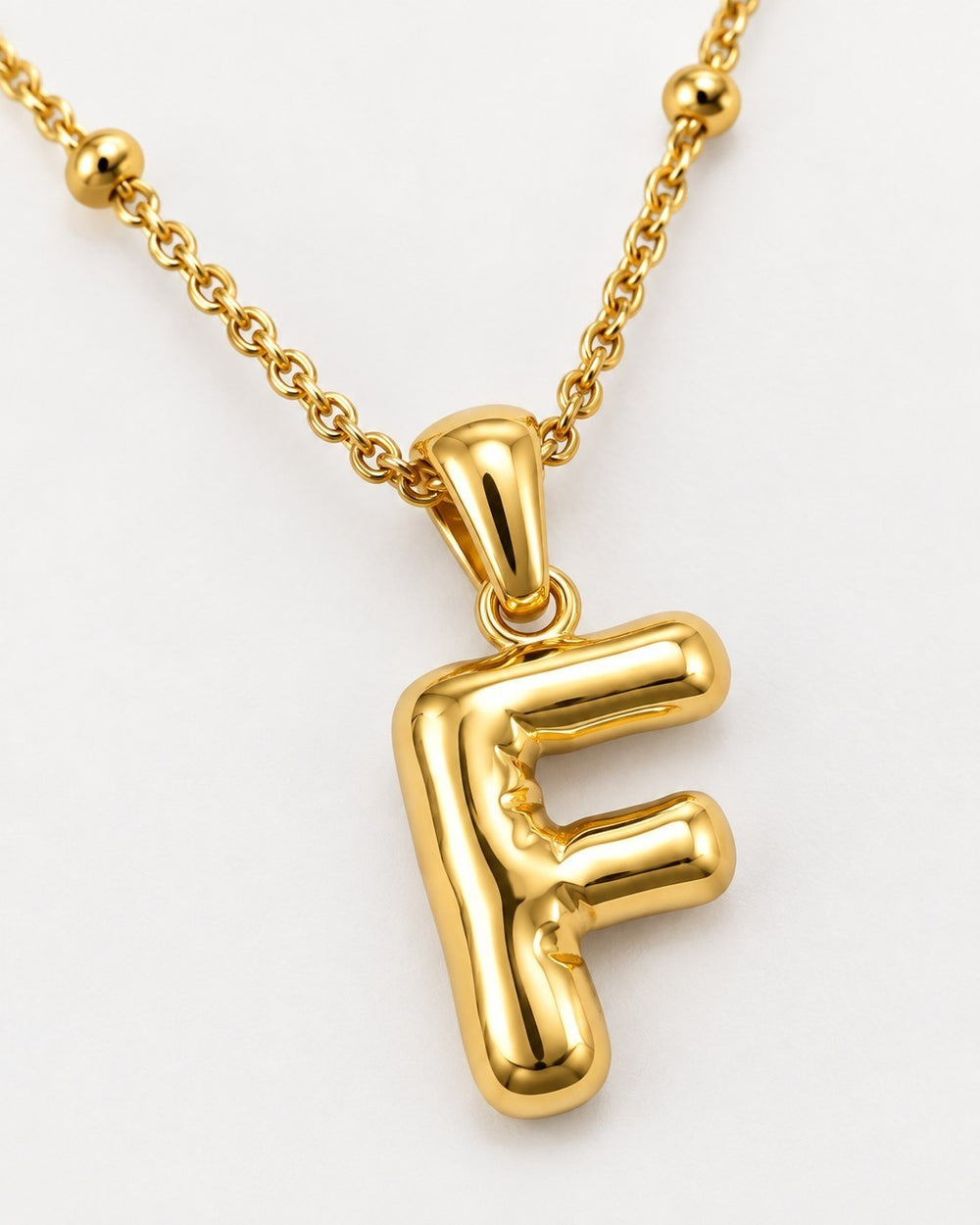 Elli Jewellery gold plated chunky initial F pendant necklace on a delicate beaded chain against a white background