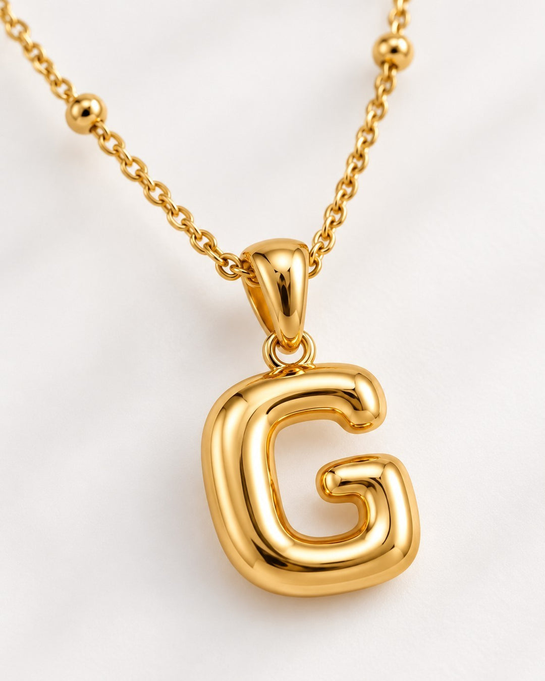 Elli Jewellery gold plated chunky initial G pendant necklace on a delicate beaded chain against a white background
