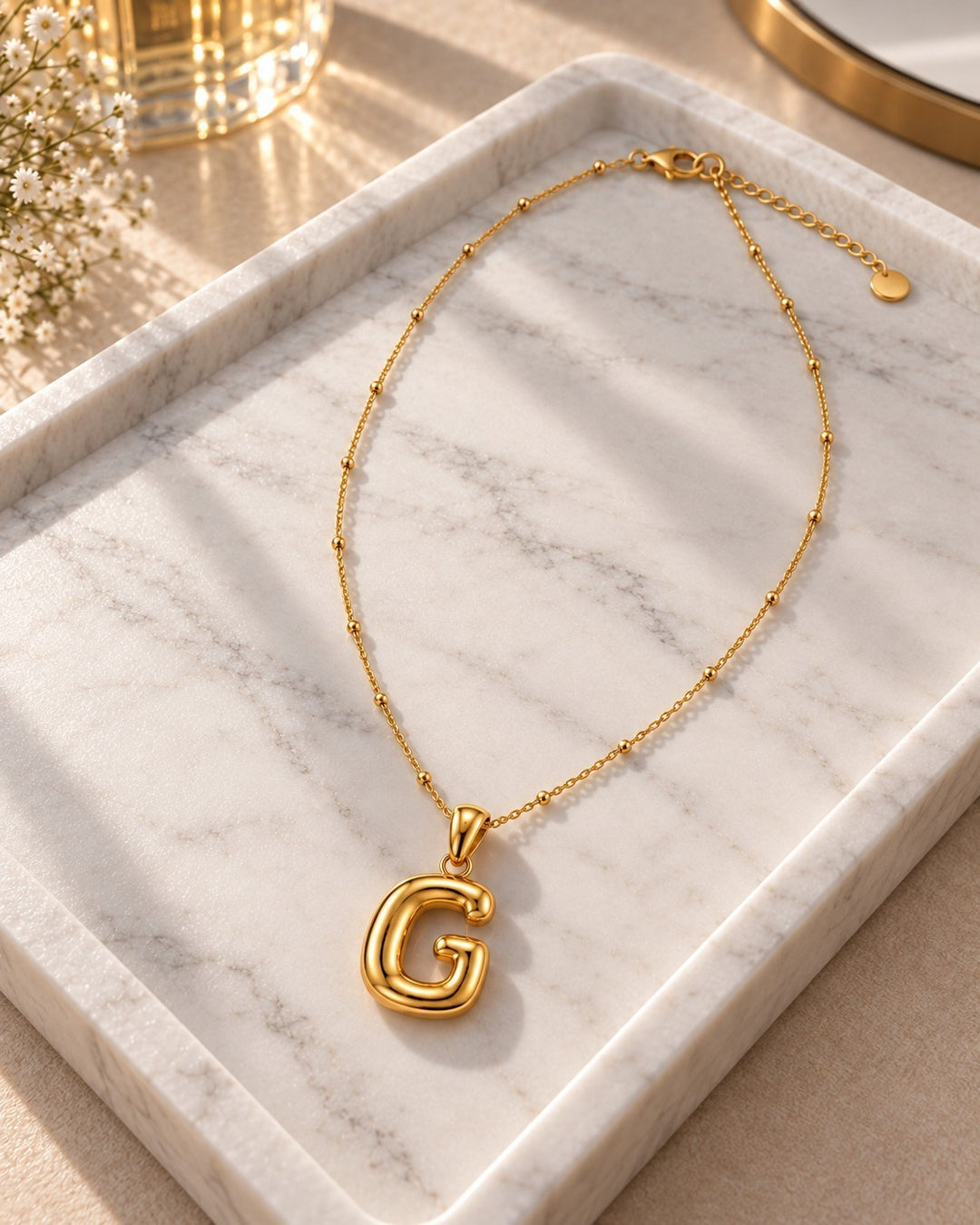 Elli Jewellery gold plated chunky initial G pendant necklace on a white marble tray with delicate beaded chain detail