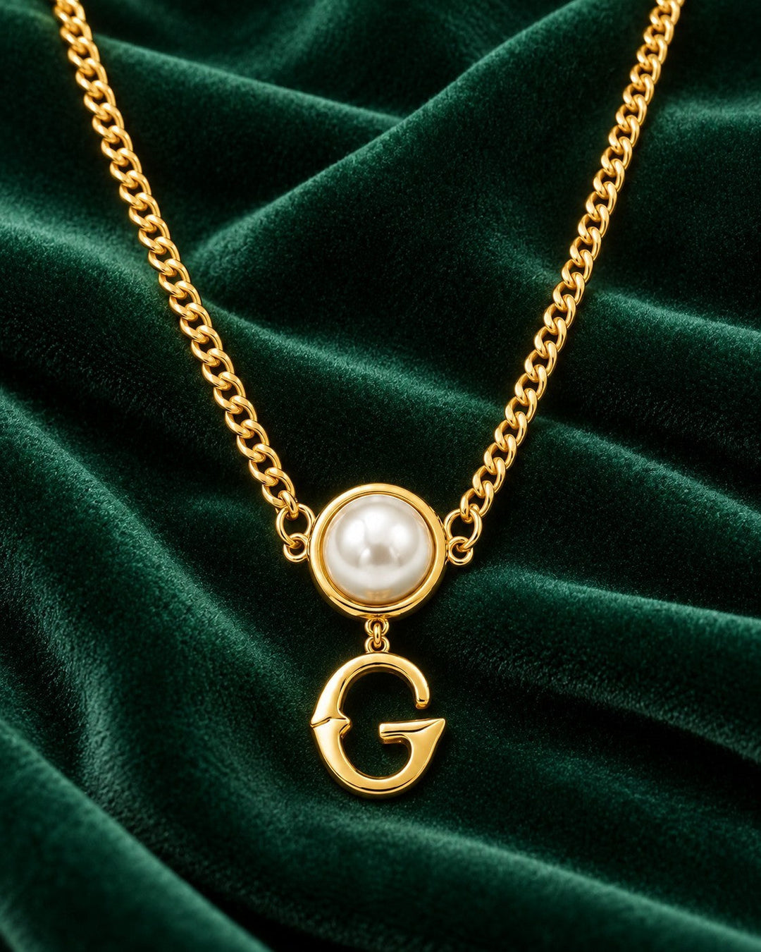 Elli Jewellery gold plated curb chain necklace featuring a pearl accent and a letter G initial pendant on green velvet