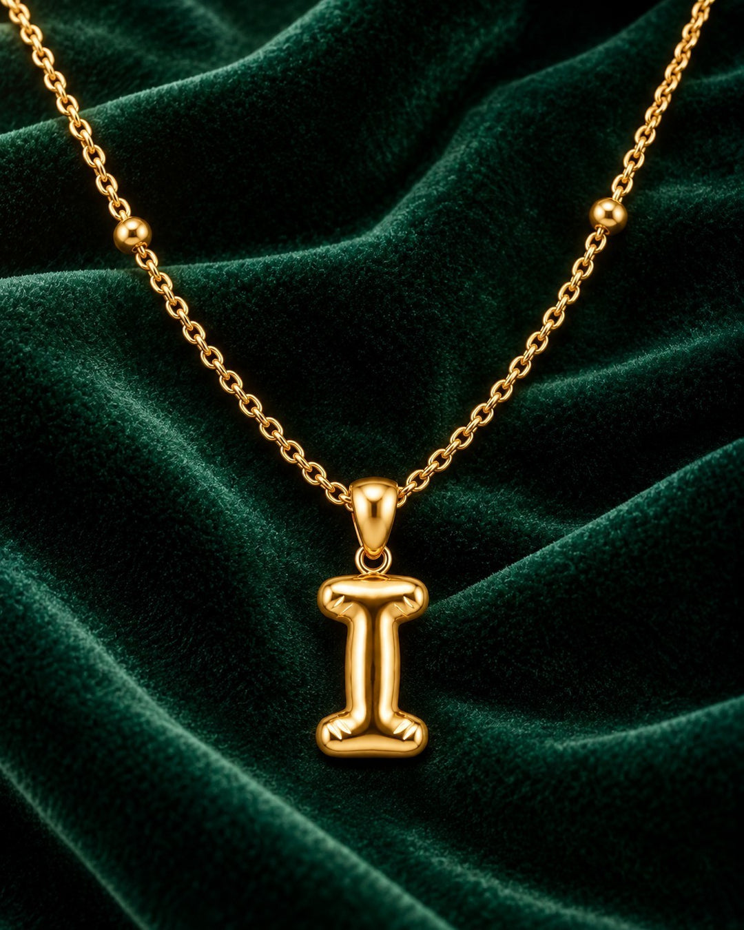 Elli Jewellery gold plated chunky initial I pendant necklace on a luxurious dark green velvet background