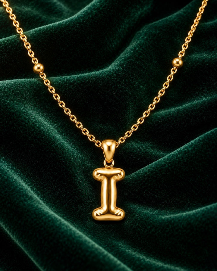 Elli Jewellery gold plated chunky initial I pendant necklace on a luxurious dark green velvet background