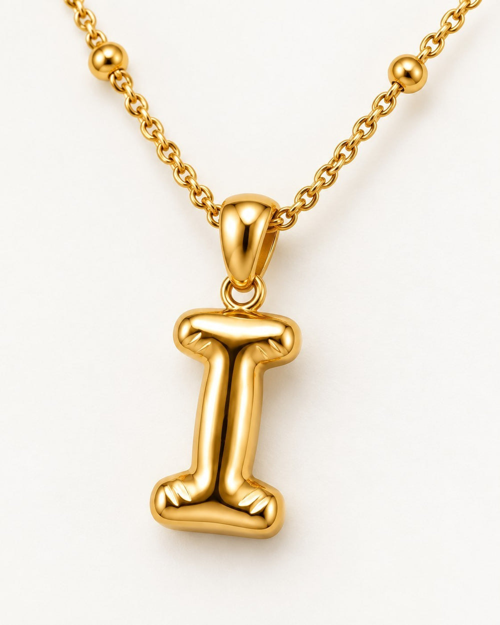 Elli Jewellery gold plated waterproof chunky initial I pendant necklace on a beaded chain against a white background.