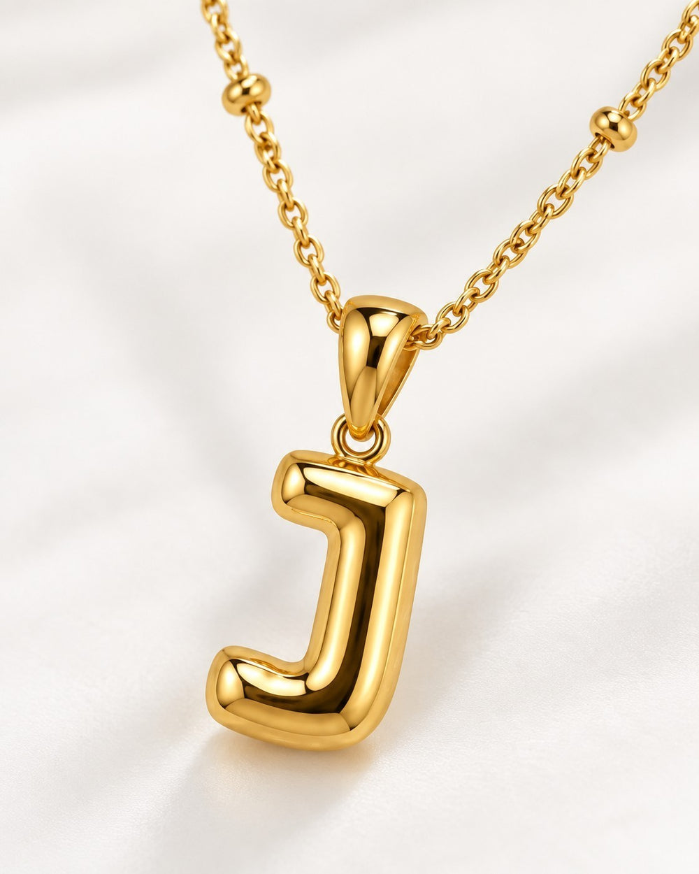 Elli Jewellery gold plated chunky initial J pendant necklace on a delicate beaded chain against a white background