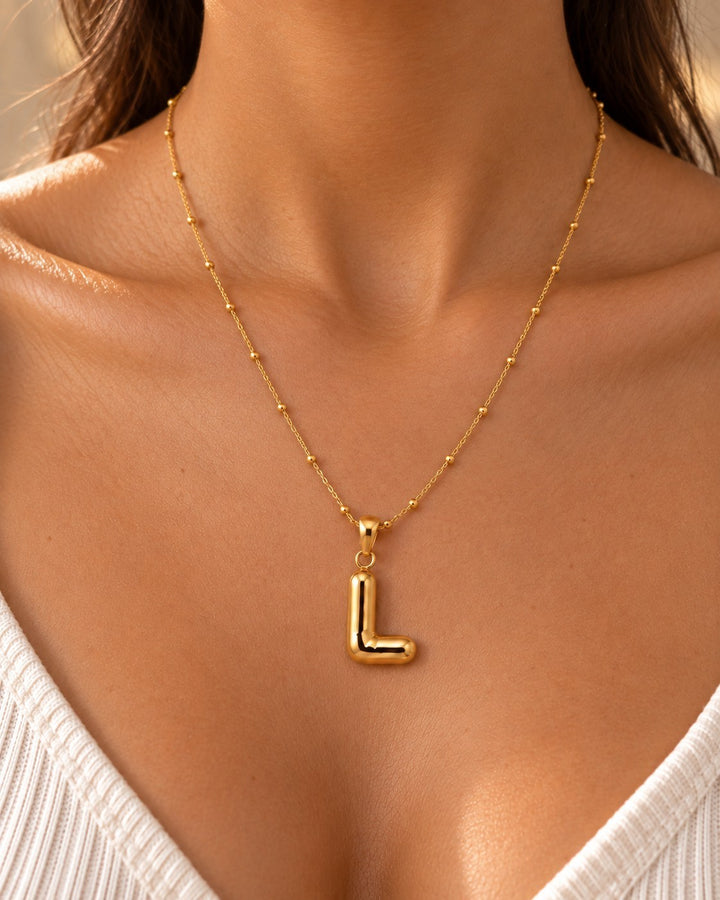 Elli Jewellery gold plated initial L pendant necklace on a delicate beaded chain worn by a woman